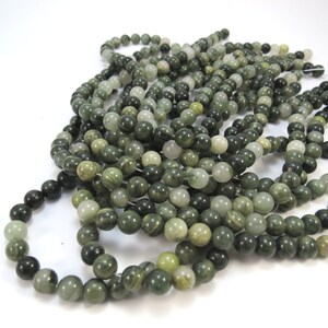 May include: A strand of green and white jade beads. The beads are round and have a smooth, polished finish. The beads are strung on a clear thread.