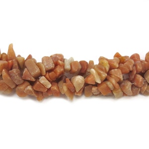 May include: A strand of chip-shaped carnelian gemstone beads. The beads are a mix of light and dark orange colors.