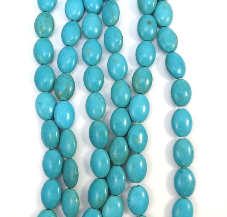 May include: A strand of turquoise oval beads. The beads are a bright, vibrant blue color and have a smooth, polished finish.