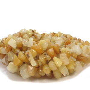 May include: A pile of yellow and white tumbled stone beads. The beads are various shapes and sizes.