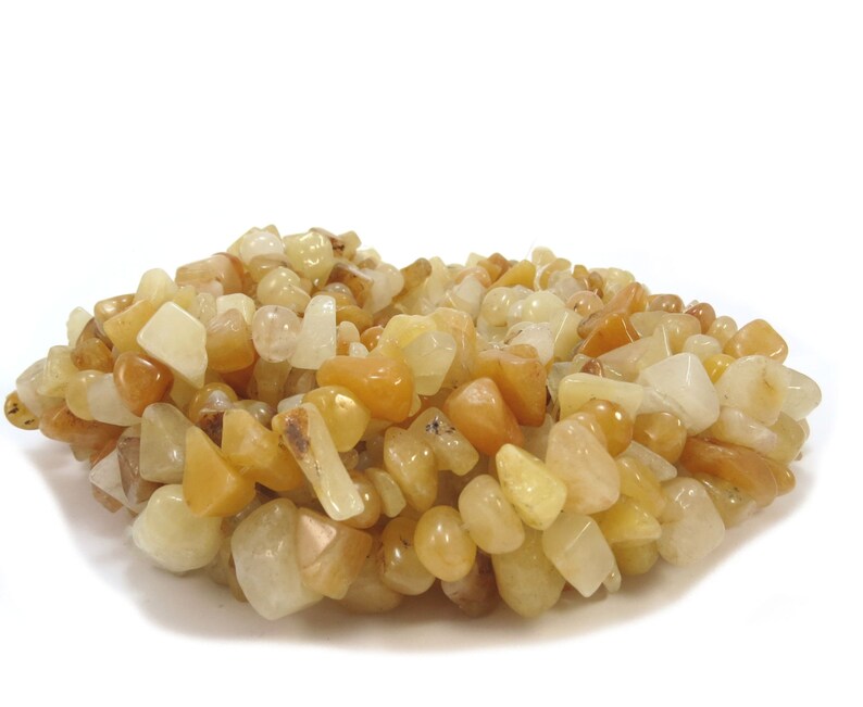 May include: A pile of yellow and white tumbled stone beads. The beads are various shapes and sizes.