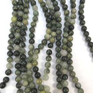May include: A strand of green and white striped round beads. The beads are made of natural stone and have a smooth, polished finish.