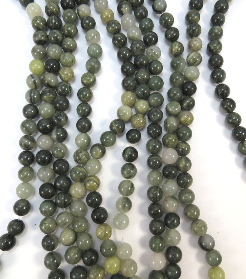 May include: A strand of green and white striped round beads. The beads are made of natural stone and have a smooth, polished finish.