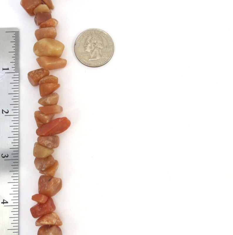 May include: A strand of orange and yellow gemstone beads, approximately 4 inches long, next to a US quarter for size comparison.