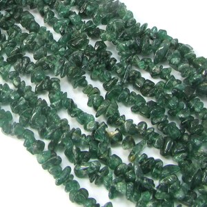 May include: A strand of green gemstone chips, also known as green aventurine, for jewellery making. The chips are irregular in shape and have a translucent appearance.