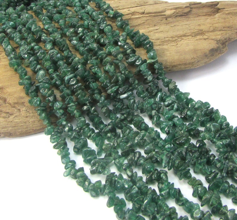 May include: A strand of green aventurine chip beads. The beads are small and irregular in shape, and they have a slightly translucent appearance.