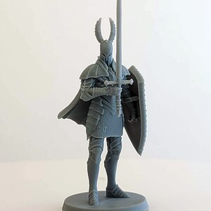 May include: A gray 3D printed miniature of a knight in full armor, holding a sword and shield. The knight has a horned helmet and a flowing cape.