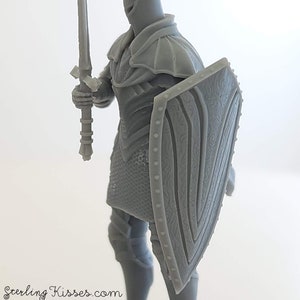 May include: A gray plastic miniature of a knight wearing armor and holding a sword and shield. The shield has a detailed design.