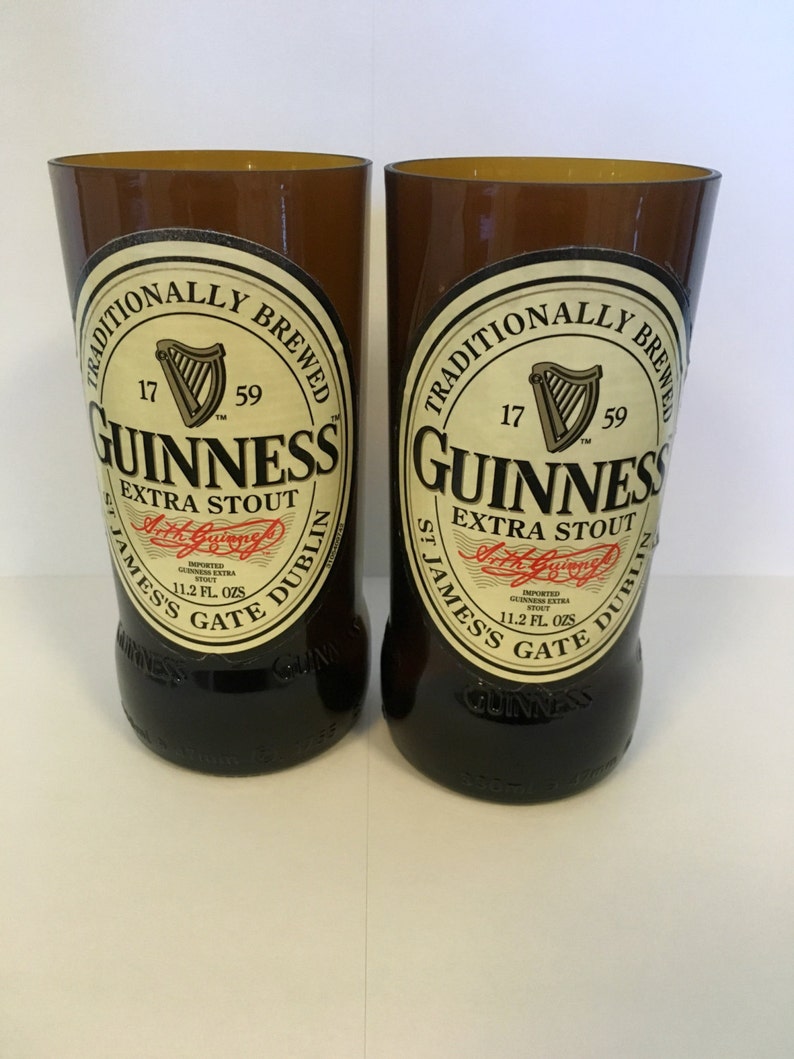 May include: Two brown glass beer bottles with a white label that reads "Traditionally Brewed 17 59 Guinness Extra Stout St. James's Gate Dublin" and a red label that reads "Imported Guinness Extra Stout 11.2 Fl. Ozs."