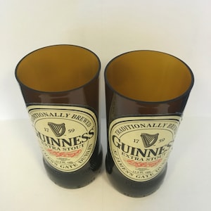 May include: Two brown glass beer bottles with the Guinness logo and text "Traditionally Brewed 17 59 Guinness Extra Stout St. James's Gate Dublin 11.2 Fl. Ozs."