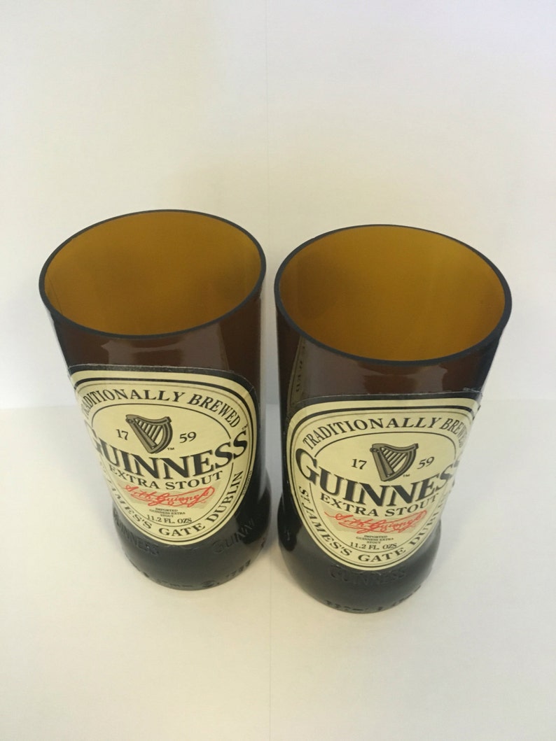 May include: Two brown glass beer bottles with the Guinness logo and text "Traditionally Brewed 17 59 Guinness Extra Stout St. James's Gate Dublin 11.2 Fl. Ozs."