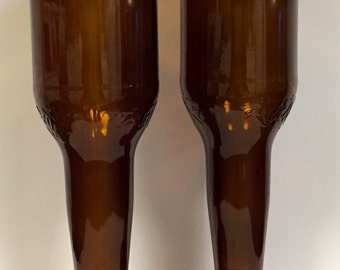 May include: Two brown glass bottles with the tops cut off and the bottoms used as bases. The bottles are clear and have a smooth, shiny finish.