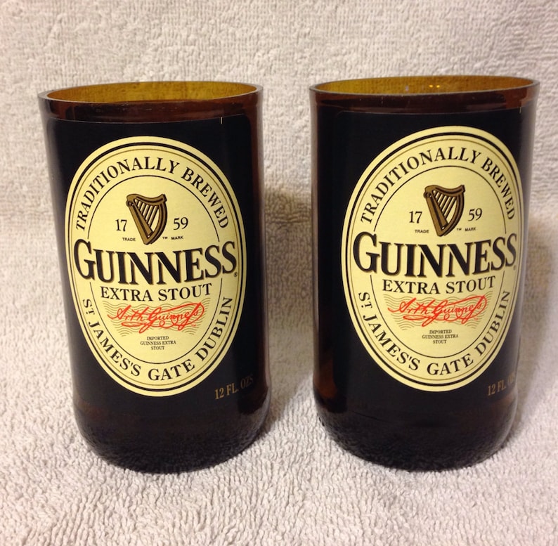 May include: Two brown glass beer bottles with black labels. The labels feature the Guinness logo, the text "Traditionally Brewed", "Guinness Extra Stout", "St. James's Gate Dublin", and "12 fl oz".