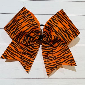May include: Orange and black cheer bow with a tiger stripe pattern.