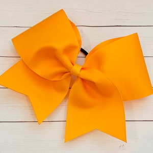 May include: A large, bright yellow cheer bow with a black elastic band.