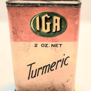 May include: Vintage IGA turmeric spice tin. The rectangular tin has a faded pink and cream color scheme. The IGA logo is in a green oval. The text "2 OZ. NET" and "Turmeric" are printed on the tin.