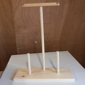 May include: Wooden stand with three dowels, designed for displaying items like jewelry or scarves.
