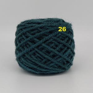May include: A ball of teal-colored yarn with the number 26 in yellow. The yarn is tightly wound, showing the texture of the fibers. This yarn is suitable for knitting or crocheting projects.