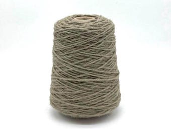 May include: A cone of natural-colored yarn, likely wool or a similar fiber, is centered against a white background. The yarn is tightly wound, forming a conical shape. The color is a muted, earthy tone, suggesting a natural, undyed material. The yarn is suitable for knitting or crocheting.