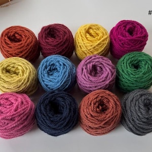 May include: Twelve round balls of yarn arranged in a grid, featuring a variety of colors including rust, burgundy, yellow, magenta, mustard, blue, purple, green, pink, navy, terracotta, and charcoal gray, with the text #1 in the top right corner.