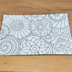 Peut inclure: Un dessin au trait noir et blanc d'un motif de mandala avec différentes formes géométriques, y compris des cercles, des fleurs et des feuilles.