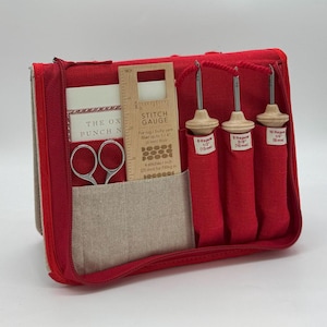 May include: Red zippered pouch with a linen interior containing a set of three wooden punch needles, a pair of scissors, and a wooden stitch gauge with the text "The Oxford Punch Needle" and "Stitch Gauge" printed on it.