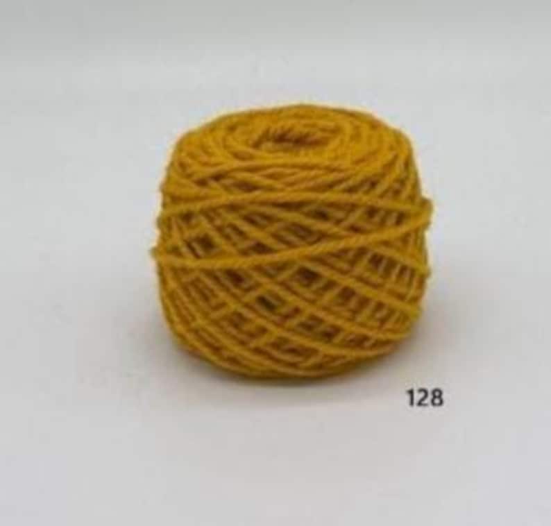 May include: A ball of mustard yellow yarn, tightly wound, with visible texture. The yarn is a solid colour, and the number "128" is printed on the lower right corner. The yarn appears to be made of wool or a similar fibre.