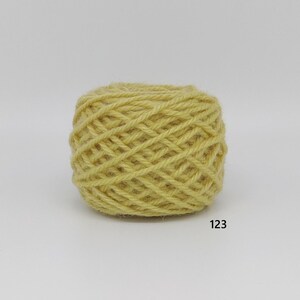 May include: A ball of yellow yarn, tightly wound, with a textured surface. The yarn is a light, muted yellow colour. The number "123" is printed in black on the bottom right.