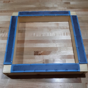 May include: A wooden frame with blue and gray trim. The frame is made of wood and has a rectangular shape. The trim is made of a soft, flexible material and has a textured surface.