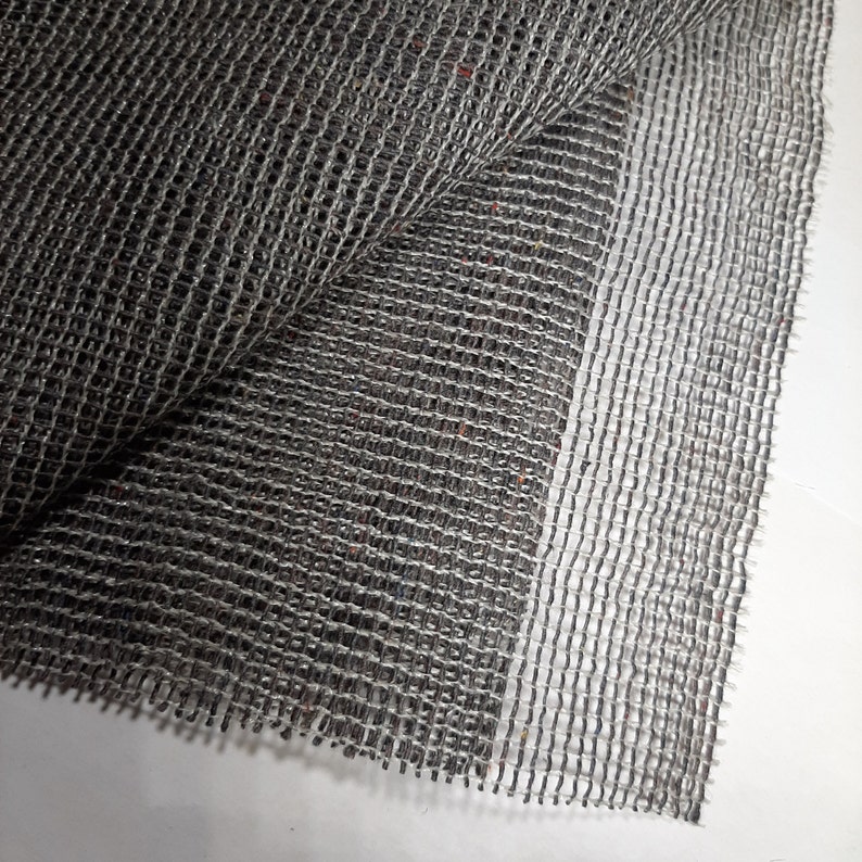 May include: A close-up of a gray, woven mesh fabric. The fabric has a slightly textured surface and is folded in half.
