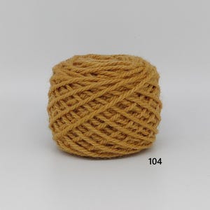 May include: A ball of mustard-yellow yarn, tightly wound with visible texture. The number "104" is printed in black on the lower right. Suitable for knitting, crochet, or other yarn crafts.