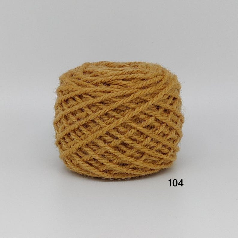 May include: A ball of mustard-yellow yarn, tightly wound with visible texture. The number "104" is printed in black on the lower right. Suitable for knitting, crochet, or other yarn crafts.