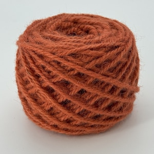Peut inclure: Une pelote de laine orange, enroulée en une bobine bien rangée.
