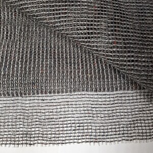 May include: Close-up of a gray, woven mesh fabric with a fine, even texture. The fabric is folded over itself, revealing the underside of the mesh.