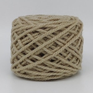 Peut inclure: Une pelote de laine beige, prête à être tricotée ou crochetée.