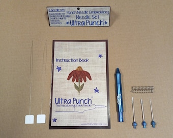 May include: A punch needle embroidery kit with three needles, a punch tool, an instruction booklet, and a small wooden sign that reads "Punch Needle Embroidery Needle Set *Ultra Punch*"