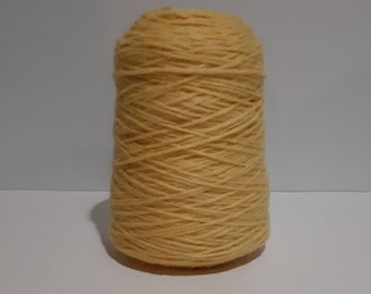 May include: A spool of yellow yarn, tightly wound, stands against a plain background. The yarn is a warm, golden color, and the texture of the individual strands is visible. This yarn is suitable for various knitting and crochet projects.