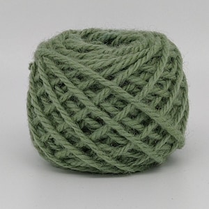 Peut inclure: Une pelote de laine vert sauge, étroitement enroulée avec une texture visible. La laine semble être une fibre naturelle, adaptée aux projets de tricot ou de crochet. La couleur est une teinte sourde et terreuse.