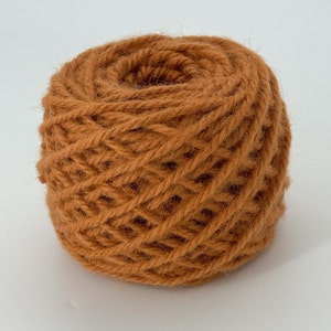 Peut inclure: Une pelote de laine orange, enroulée en une bobine serrée.