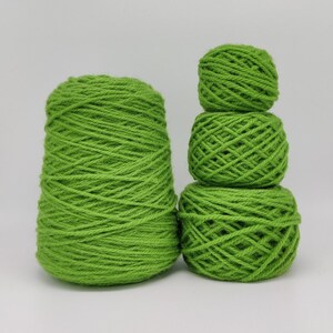May include: Three balls of bright green yarn, one large ball and two smaller balls stacked on top of each other.