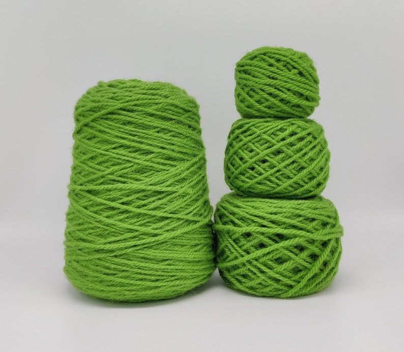 May include: Three balls of bright green yarn, one large ball and two smaller balls stacked on top of each other.
