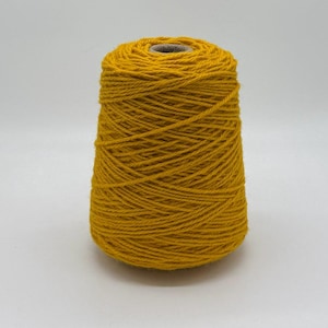 May include: A cone of mustard yellow yarn, ideal for knitting or crochet projects. The yarn is tightly wound, creating a textured surface. The cone shape allows for easy dispensing of the yarn during crafting. The yarn is a solid color, perfect for various projects.