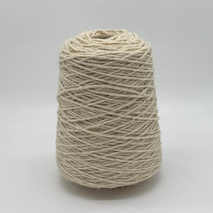 May include: A cone of natural-colored yarn, ideal for knitting or crocheting projects. The yarn is tightly wound, creating a textured surface. The neutral color makes it suitable for various craft projects.