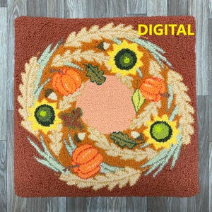 Peut inclure: Un motif numérique pour un tapis de point d'aiguille représentant une couronne de feuilles d'automne, de citrouilles et de tournesols. La couronne est sur un fond brun. Le texte "DIGITAL" est dans le coin supérieur droit de l'image.