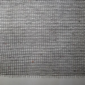 May include: A close-up of a black and white woven mesh fabric with a slightly frayed edge.