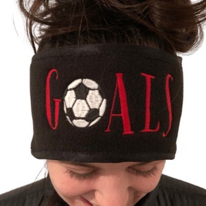 May include: Black fleece headband with red embroidered text "GOALS" and a white and black soccer ball graphic.