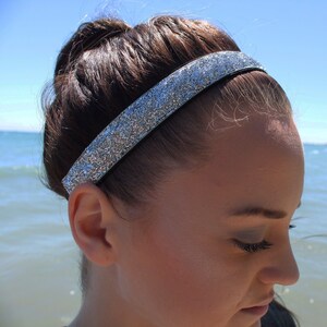 May include: A silver glitter headband for women. The headband is made of a stretchy material and is designed to be worn around the forehead.