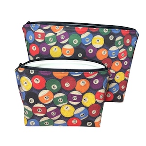 May include: Two zippered pouches with a black background and a pattern of colorful billiard balls with white numbers. The larger pouch is on top of the smaller pouch.