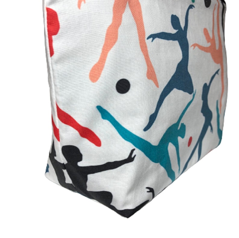 White cotton makeup bag with a colorful print of dancers in various poses. The dancers are silhouetted in shades of red, blue, teal, and pink.