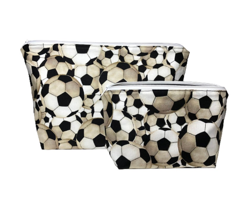 Two zippered pouches with a black and white soccer ball pattern. The larger pouch is in the background and the smaller pouch is in the foreground.